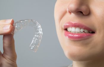 A woman holding Invisalign aligner in her hand