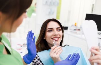 A dentist and a woman in a dental chair choosing the size of dental veneers.