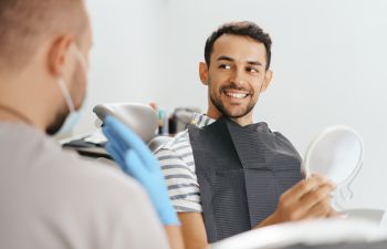 A dentist and a happy man after restorative treatment sitting in a dental chair.