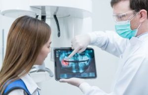 Dentist showing didgital teeth imaging and explaining treatment to a woman patient.